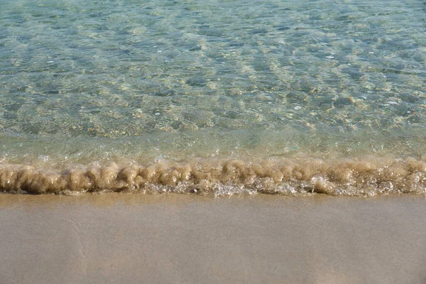 Olas claras y arena colorida en la playa de arena tropical en Creta Grecia. —  Fotos de Stock