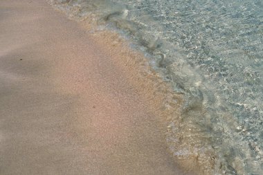 Girit 'teki tropikal kumlu sahilde berrak dalgalar ve renkli kumlar