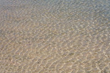 Girit 'teki tropikal kumlu plajda temiz suyun yüzeyi