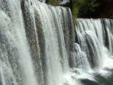 Sonbahar şelalesi neşe dolu mavi-yeşildi. Kırmızılar ve altınlar arasında istikrarlı bir şarkı..