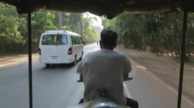 A stabilized shot from behind a tuk tuk passenger seat in southeast asia during summer month