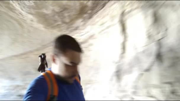 Hombre Con Mochila Caminando Través Una Cueva Sosteniendo Una Cámara — Vídeo de stock