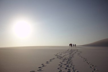 Brezilya 'da gün batımında bir kum tepesinde yürüyen turistler