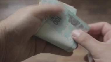 Brezilya Real 'in para banknotlarını tutan ve sayan bir adamın yakın plan fotoğrafı.