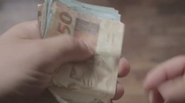 Brezilya Real 'in para banknotlarını tutan ve sayan bir adamın yakın plan fotoğrafı.