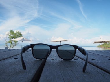 Sahilde ahşap bir gemide yerleştirilen siyah güneş gözlüğü.