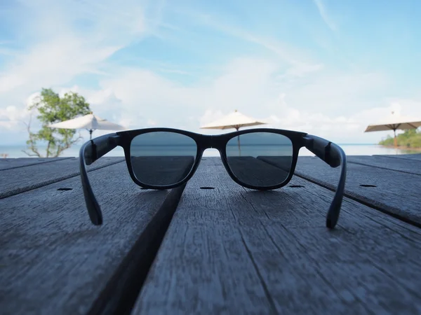 Sahilde ahşap bir gemide yerleştirilen siyah güneş gözlüğü.