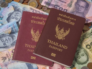 Sikke ve banknot baht para yığını üzerinde Tayland pasaportu.