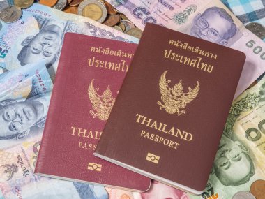 Sikke ve banknot baht para yığını üzerinde Tayland pasaportu.