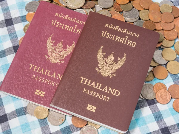 Pasaporte de Tailandia en la pila de monedas baht moneda, sobre el fondo de seda taparrabos . — Foto de Stock