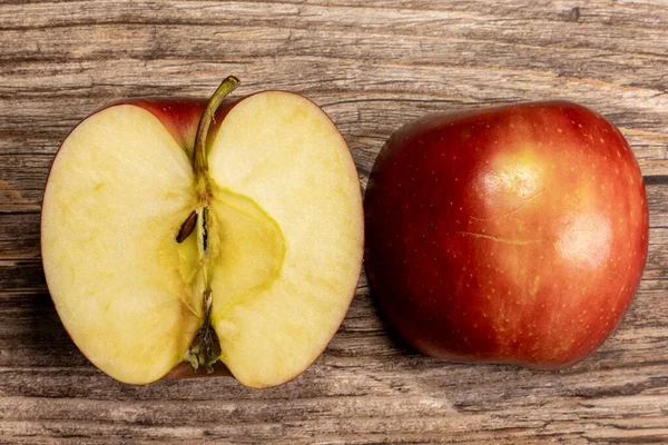 Kırmızı elmanın iki yarısı yukarıdan ahşap bir masada, yakın plan.