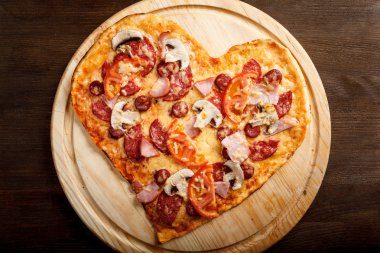 Pizza kalp şekli üzerinde koyu ahşap arka plan Üstten Görünüm
