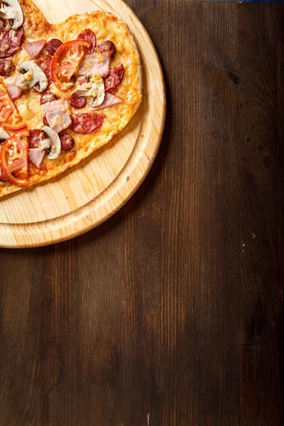 Pizza kalp şekli üzerinde koyu ahşap arka plan Üstten Görünüm