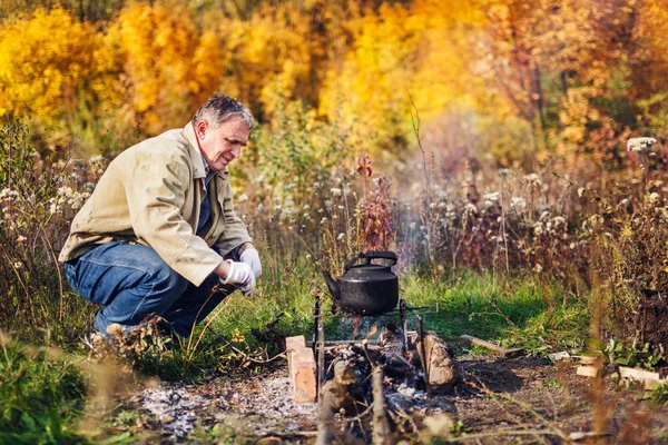 Man boils sooty kettle on the fire — Stockfoto