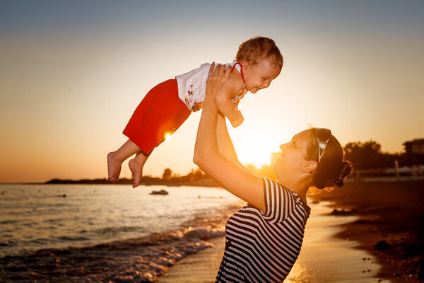 Siluhettes of mother and son by the sea at sunset