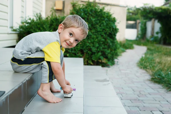Boy sitting on stairs in back of  his house smiling — Stock Photo, Image