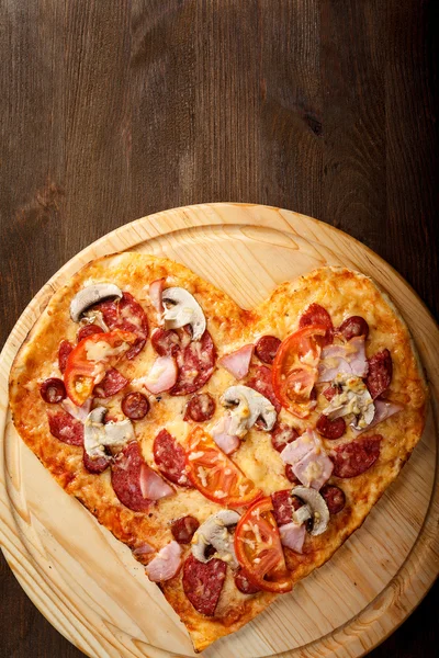Forma de coração de pizza no fundo de madeira escura vista superior — Fotografia de Stock