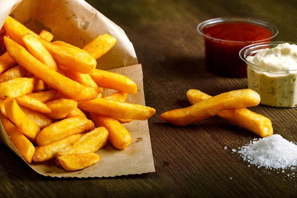 Tahta arka planda ketçaplı taze kızarmış patates kızartması.