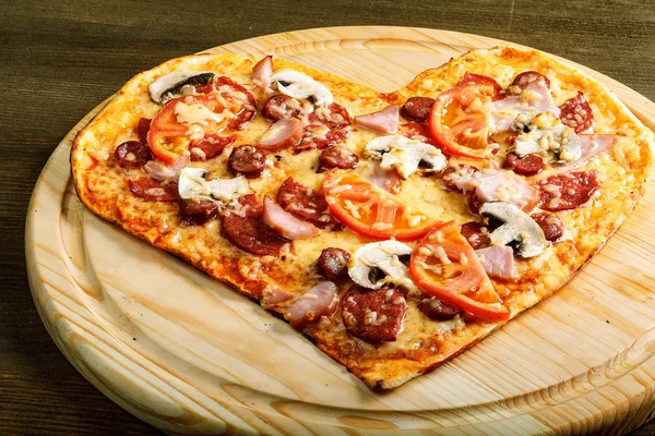 Pizza heart shape on dark wooden background top view