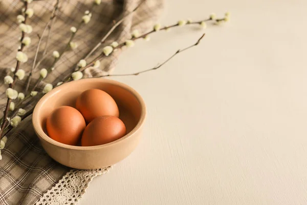 Easter eggs in natural color in a ceramic plate with pussy willow branches.