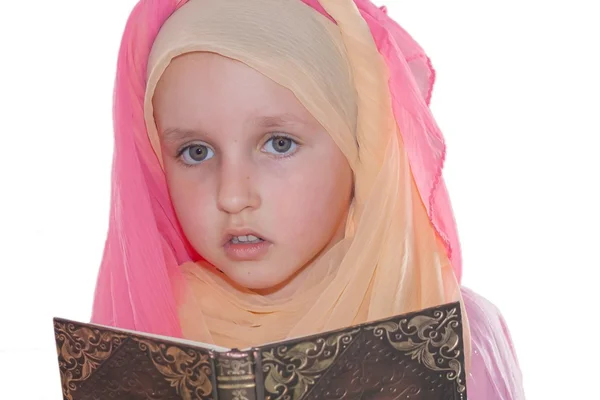 The girl in a scarf before a prayer . Interesting book — Stock Photo, Image
