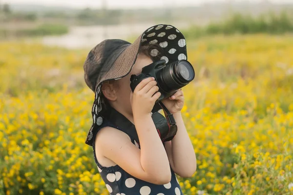Menina, câmera reflexa e campo. Um fundo de verão — Fotografia de Stock