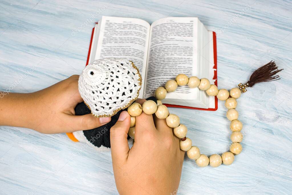 children's hands with rosary and prayer book on the table, background of religion