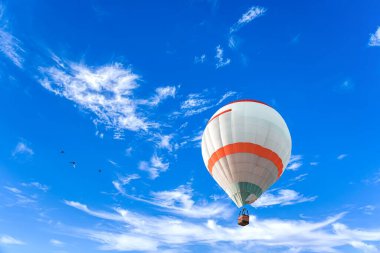 Mavi gökyüzünün ortasında bir balon. Bulutlarda süzül