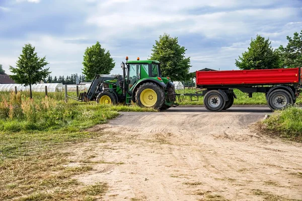 tractor with trailer on rural road , fork loader