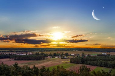 Bulutlu gökyüzünde güzel bir gün batımı. genç ay