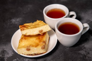 İki fincan çay, bir fincan tabağında süzme peynir güveci. Kahvaltıda. Yakın plan. Seçici odak.