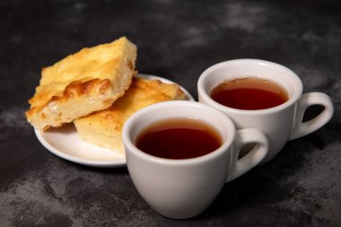 İki fincan çay, bir fincan tabağında süzme peynir güveci. Kahvaltıda. Yakın plan. Seçici odak.