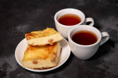 İki fincan çay, bir fincan tabağında süzme peynir güveci. Kahvaltıda. Yakın plan. Seçici odak.