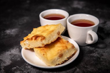 İki fincan çay, bir fincan tabağında süzme peynir güveci. Kahvaltıda. Yakın plan. Seçici odak.