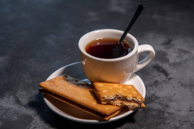 Çay ya da çay, çay fincanında çay kaşığı ve kurabiyeyle. Yakın plan. Seçici odak.