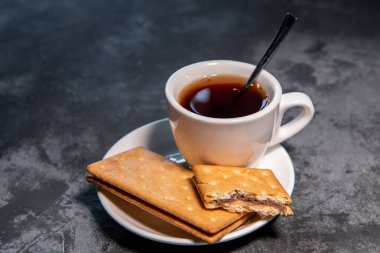 Çay ya da çay, çay fincanında çay kaşığı ve kurabiyeyle. Yakın plan. Seçici odak.