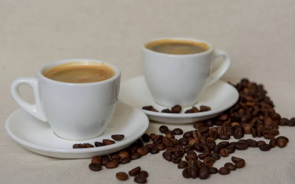 Dwie Filiżanki Mocnej Kawy Kawa Białym Kubku Spodku Ziarna Kawy — Zdjęcie stockowe