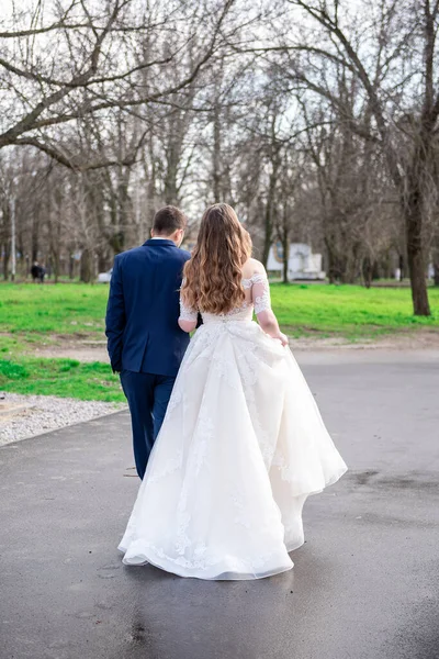 The bride and groom stand back, hold hands.