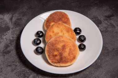 Süzme peynirli krep, böğürtlenli şurup ve masada yakın plan ekşi krema. Geleneksel Rus / Ukrayna mutfağı, kahvaltı