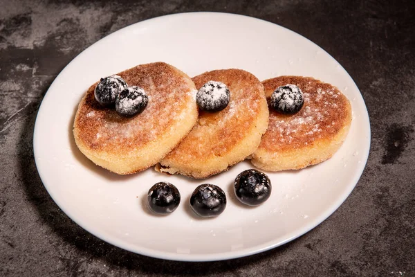 健康的早餐 小吃奶酪煎饼 蓝莓和酸奶油的特写在桌上的盘子里 俄罗斯 乌克兰传统烹饪 — 图库照片