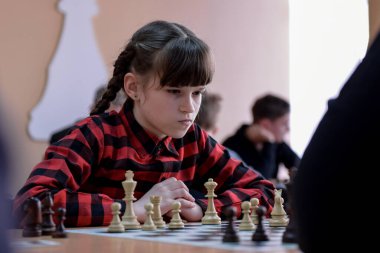 Satranç tahtasındaki kız. Rekabet. Satranç turnuvası. Kız satranç oynuyor. Kız çocuğa karşı satranç oynuyor. Satranç oyunu. Portre