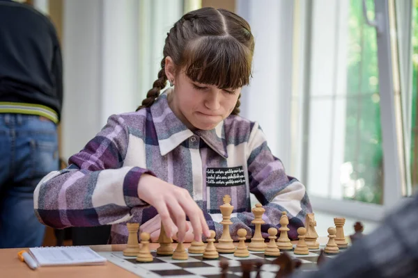 The girl at the chessboard. Competition. Chess tournament. The girl plays chess. The girl against the boy plays chess. Game of chess. Portrait