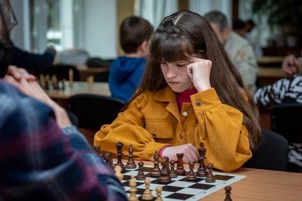 The girl at the chessboard. Competition. Chess tournament. The girl plays chess. The girl against the boy plays chess. Game of chess. Portrait
