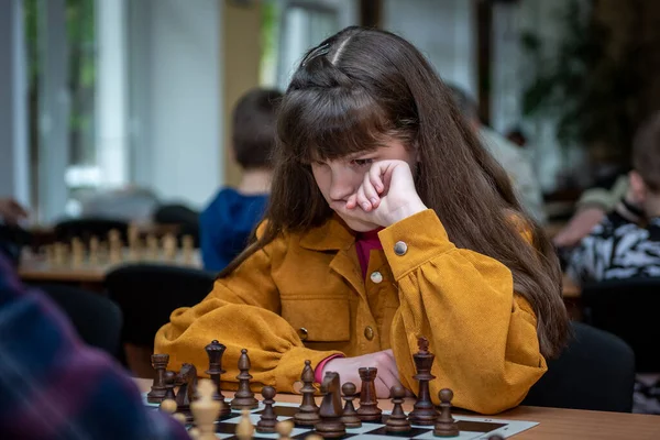 The girl at the chessboard. Competition. Chess tournament. The girl plays chess. The girl against the boy plays chess. Game of chess. Portrait