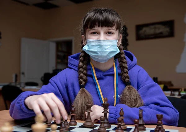 playing chess girl playing chess against boy chess tournament during quarantine girl wearing medical mask playing chess