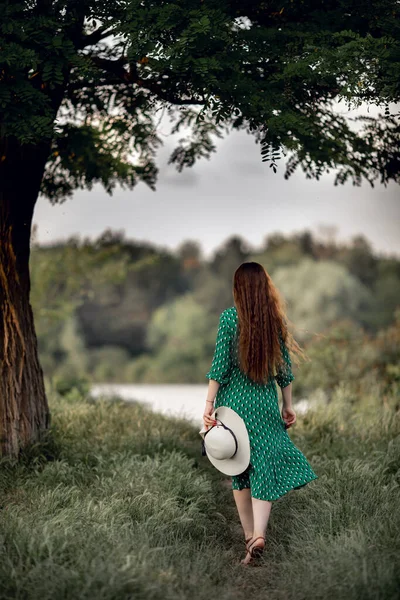 Девушка Длинными Волосами Зеленом Платье Шляпе Идет Реке Вид Сзади — стоковое фото