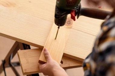 Tahta bir bankta, bir tahta parçasına vida delme matkabını kapat. Ahşap bankta çalışan bir kadın. DIY meraklısı.