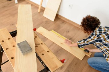 Arka planda çalışan bir kadının olduğu tezgahın üzerindeki ahşap zımpara kağıdına yakın çekim. Kapalı çekim. Doğal ışık.