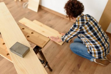 Arka planda çalışan bir kadının olduğu tezgahın üzerindeki ahşap zımpara kağıdına yakın çekim. Kapalı çekim. Doğal ışık.