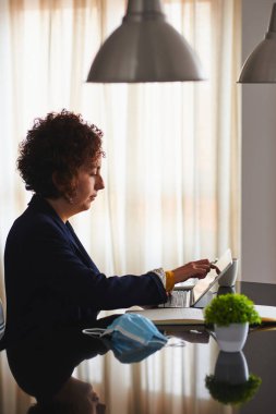 Kıvırcık saçlı, evden çalışan güzel bir kadın. Doğal ışık.